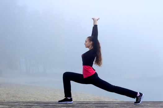 Young pretty slim fitness sporty woman does stretching exercises during training workout outdoor