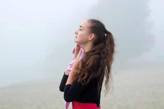 Young pretty slim fitness sporty woman with towel during break at training workout outdoor