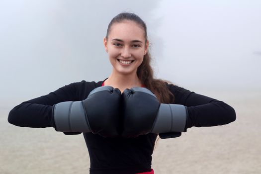 Young pretty slim fitness sporty woman does boxing exercises during training workout outdoor