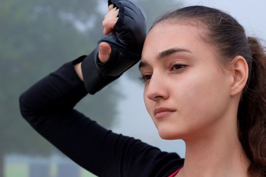 Young pretty slim fitness sporty woman rests during boxing training workout outdoor