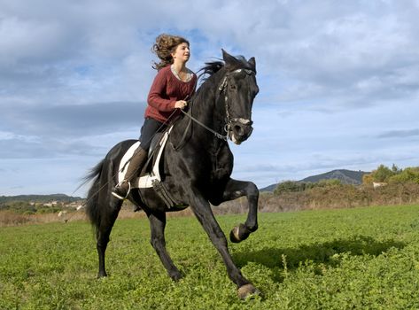 riding girl and black stallion in the nature