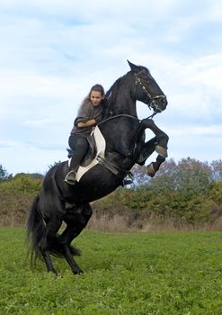riding girl and black stallion in the nature