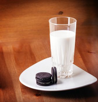Milk and cookies on a wooden table.