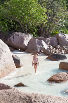 Happy woman wearing stylish bikini enjoying at amazing Anse Lazio beach on Praslin Island, Seychelles. Summer vacations on picture perfect tropical beach concept.