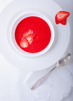 Strawberry soup served on a white plate.