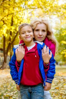 Happy mother hugging son among autumn park