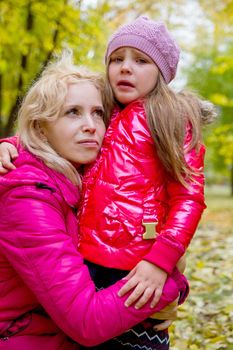 Mother comforting crying daughter in autumn park