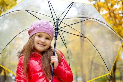 Smiling girl with umbrella on autumn back