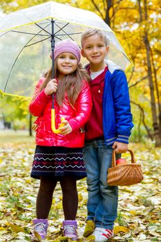 Sister and brother under umbrella in autumn