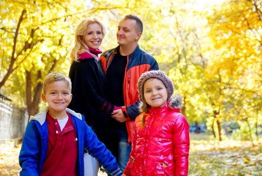 Happy family of four in autumn, children in focus