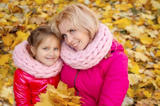 Smiling mother and daughter looking up on autumn background 