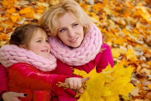 Mother and daughter on autumn background looking aside
