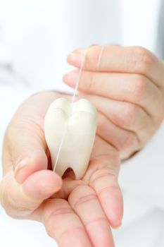 dentist holding molar with dental floss, dental concept