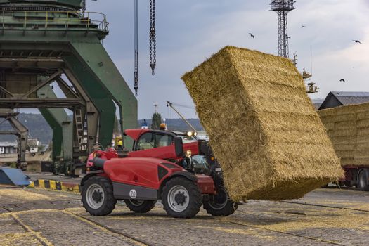 unloading bales in port from truck with telehandler