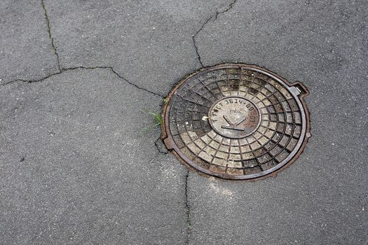 Round hatch in urban asphalt road pavement, cover sewage hatch.