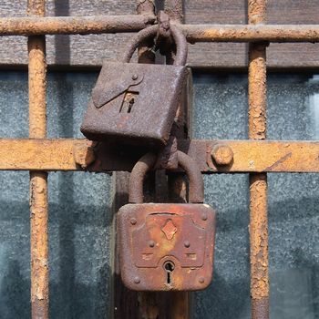 two old rusty lock on the iron bars