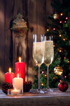 close up view of two glasses with champagne and candles on color back