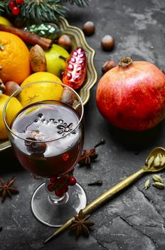 glass of mulled wine with spices on dark concrete background