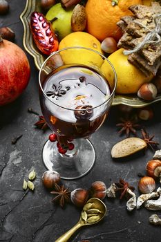 glass of mulled wine with spices on dark concrete background