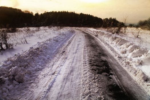 Snow covered winter road with shining streetlights in rural areas