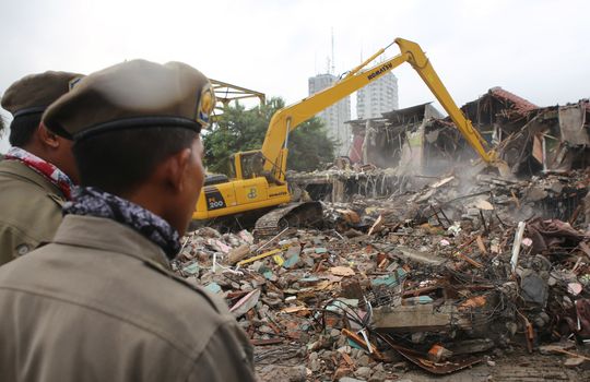 INDONESIA, Jakarta: Two policemen watches the demolition of houses of the Kalijodo red light district, in the Penjaringan subdistrict on the border of North and West Jakarta, on February 29, 2016. The neighborhood is home to about 3,000 people, including legal businesses and families. Hundreds face eviction for living among illegal brothels.