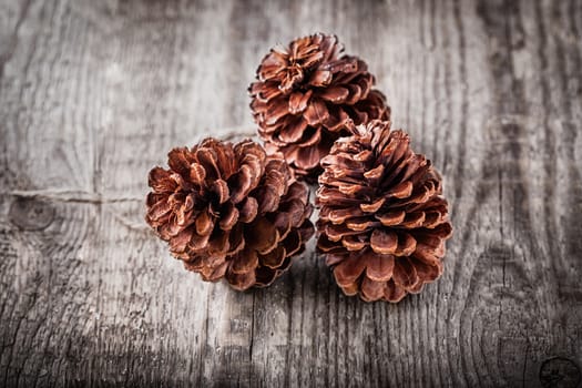 Natural wooden background with three pine cones