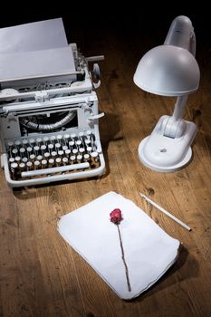Old typewriter, manuscript, pen and dry rose on a wooden table