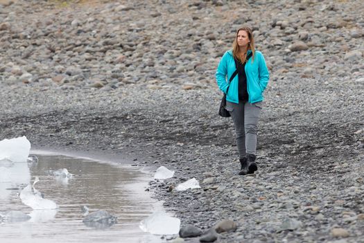 Woman walking over the beach at Jokulsarlon glacier lagoon in southern Iceland