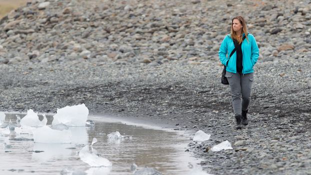 Woman walking over the beach at Jokulsarlon glacier lagoon in southern Iceland