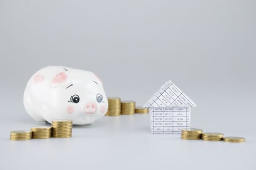 House have blur piggy bank and step pile of gold coins on white background.