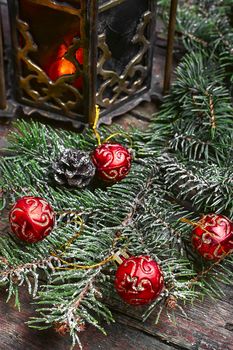 Fir branch with Christmas toys and stylish Oriental lantern with a candle