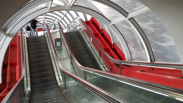 Escalator in the glass roof tunnel. Decorated in red color.