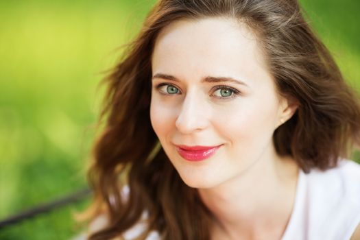 Closeup portrait of lovely urban girl outdoors. Happy smiling woman. Fashionable blonde girl sitting on a bench in a city park