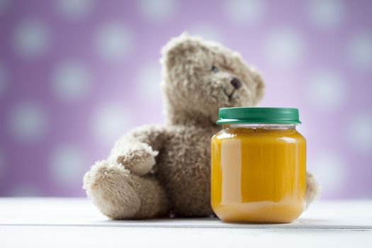 Teddy bear with jar of food on wooden table