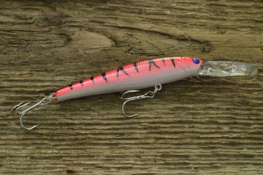 red striped wobbler for fishing on wooden background