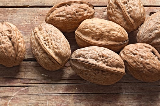 Whole unpeeled walnuts on a rough wooden background. Group of nuts in shell. Still life rustic photo.