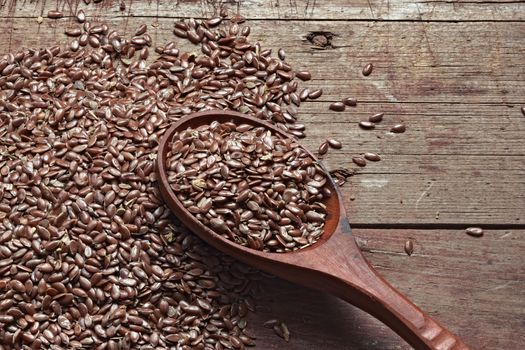Flax seeds on a rough wooden background and a spoon. Healthy products, a source of vitamins and essential fatty acids, the raw material for oil. Still life photo.
