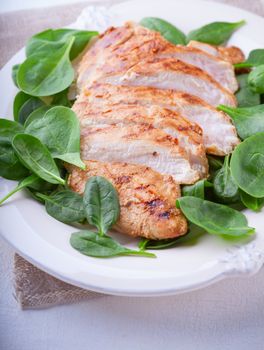 Grilled chicken breast with green leaves on a plate