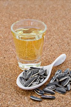 Bowl of sunflower oil and sunflower seeds on wooden background.