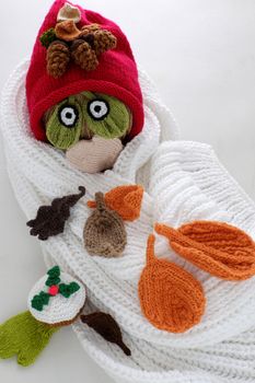 Diy funny, humor Christmas background handmade with lazy snowman from white scarf, red hat, eye and group of knitted leaf from yarn, winter leaves drop on head in cold day, art design for Xmas holiday