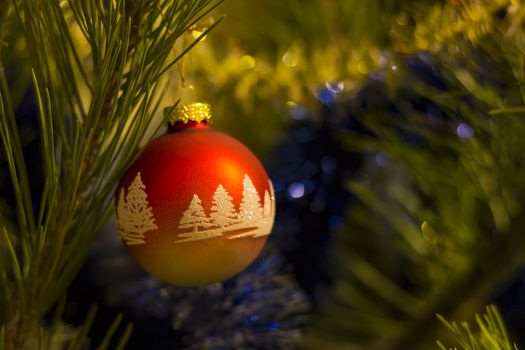 Red Christmas ball with ornaments on christmas tree. Blurred background