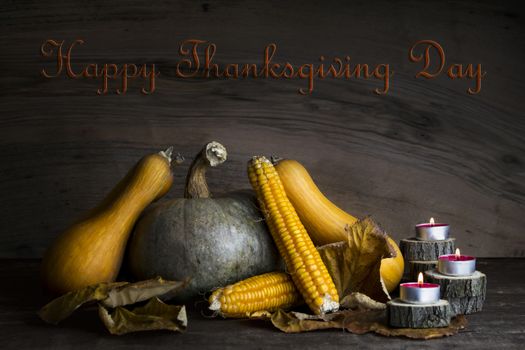 Happy Thanksgiving Day, Decoration on a wooden table with Pumpkins, Corncob, Burning Candles and autumn leaves