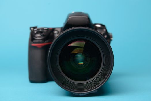 Professional modern DSLR camera against blue background