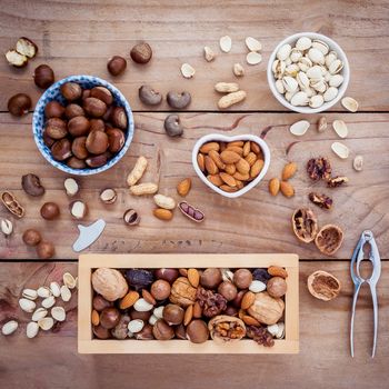 Different kinds of nuts walnuts kernels ,macadamia,hazel nuts, almond,chest nuts,cashew nuts and pistachio with nut and shell crackers on rustic wooden background.