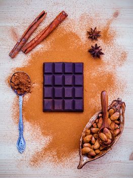 Desserts background and menu design. Brown chocolate powder in spoon , Roasted cocoa beans in the dry cocoa pod fruit and dark chocolate setup on wooden background.