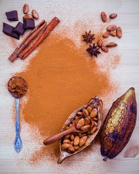 Desserts background and menu design. Brown chocolate powder in spoon , Roasted cocoa beans in the dry cocoa pod fruit and dark chocolate setup on wooden background.