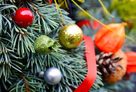 Christmas handmade decorative wreath with small ornaments and red ribbons on wooden background.