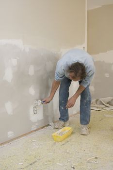 Sheetrock worker doing spot repairs on house walls, getting ready for new coat of paint, will put home on realstate market to sell 