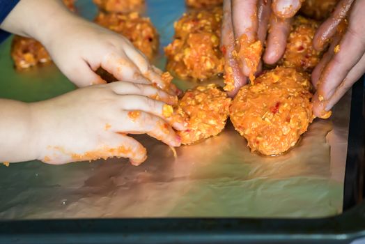 Children and dad hands put the meatballs on a baking sheet