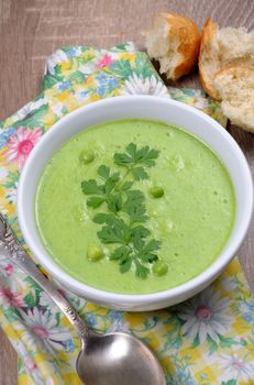 A plate of soup puree of green peas with parsley on a table